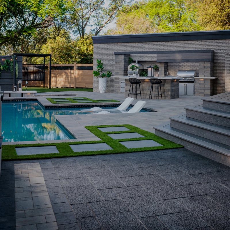 Paver pool deck with an outdoor kitchen and pergola